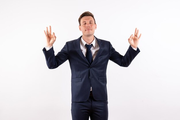 Jovem homem de frente para um elegante terno clássico com pose de meditação sobre fundo branco