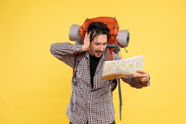 Jovem homem se preparando para uma caminhada, observando o mapa em amarelo