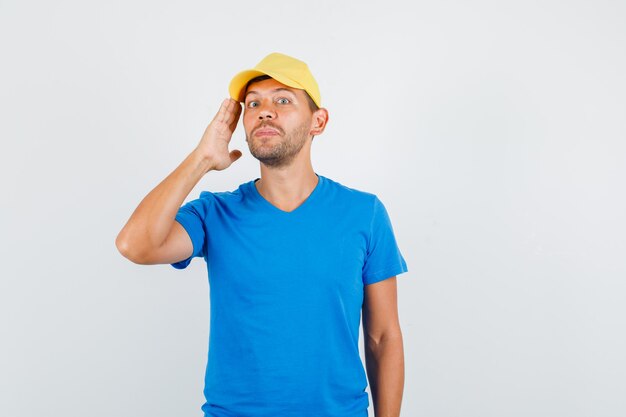 Jovem homem segurando a palma da mão perto da bochecha com camiseta azul