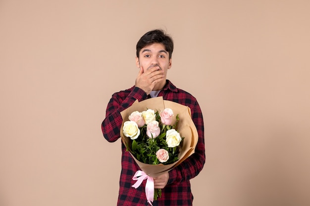 Jovem homem segurando flores bonitas na parede marrom