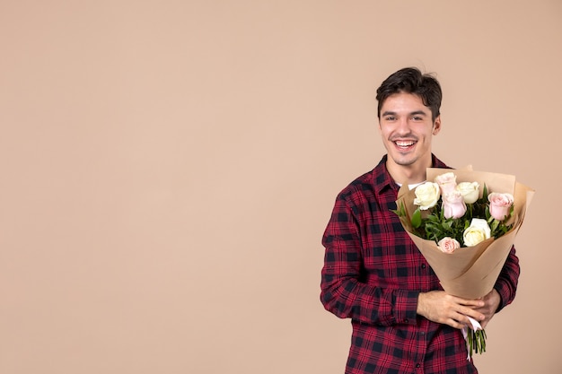 Jovem homem segurando flores bonitas na parede marrom