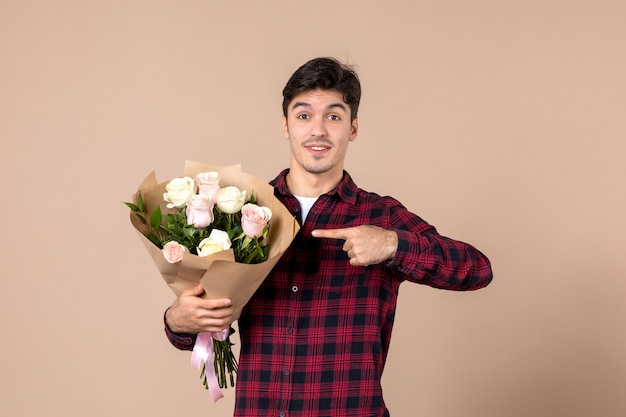 Jovem homem segurando flores bonitas na parede marrom