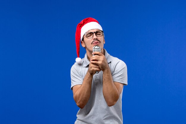 Jovem homem segurando o microfone na parede azul cantor de ano novo