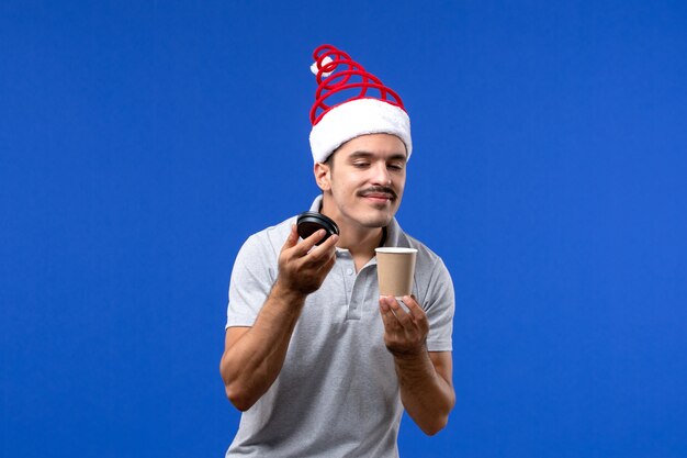 Jovem homem sentindo o cheiro de café na parede azul e emoções do feriado de ano novo masculino