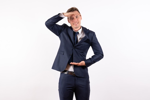 Jovem homem sorrindo de frente para um terno estrito clássico em fundo branco