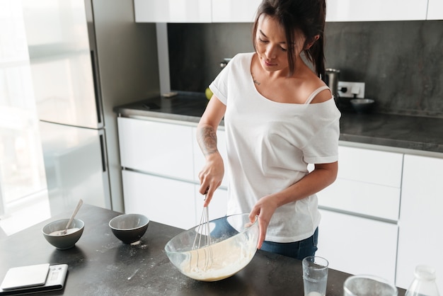 Jovem incrível em pé na cozinha em comida caseira