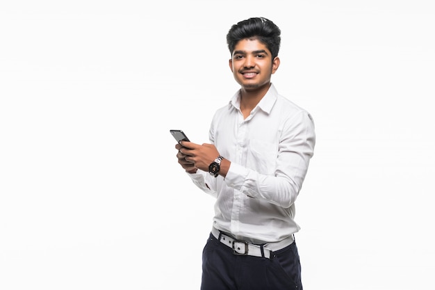 Jovem indiano bonito usando telefone celular isoated na parede branca