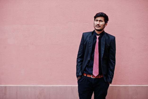 Jovem indiano de terno e gravata posou contra a parede rosa