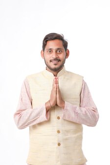 Jovem indiano em roupas tradicionais e dando namastê ou gesto de boas-vindas.