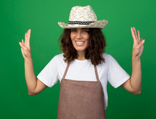 Jovem jardineira sorridente de uniforme usando chapéu de jardinagem, mostrando quatro isoladas em verde