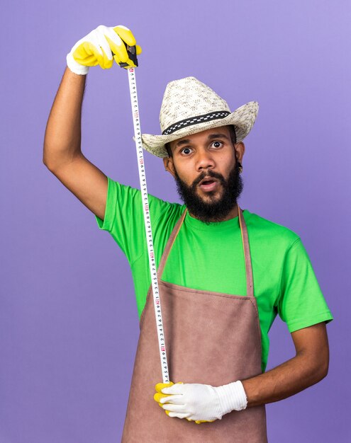 Foto grátis jovem jardineiro afro-americano surpreso com um boné de jardinagem esticando-se