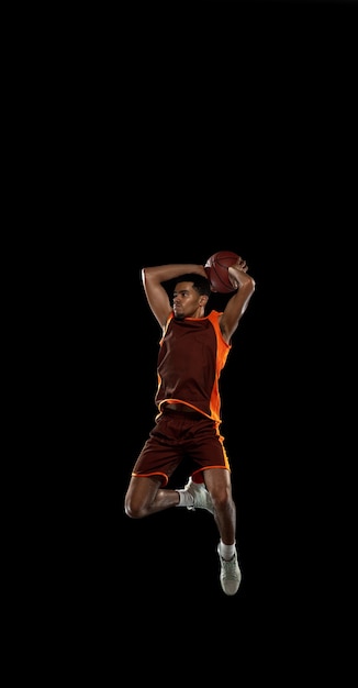 Foto grátis jovem jogador de basquete africano treinando no estúdio preto.