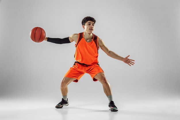 Jovem jogador de basquete da equipe vestindo treinamento sportwear, praticando em ação, movimento em execução isolado no fundo branco.