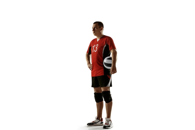 Jovem jogador de voleibol caucasiano aplacando na parede branca. Esportista masculino posando confiante com a bola, preparado para a vitória. Esporte, estilo de vida saudável, atividade, conceito de movimento. Copyspace.