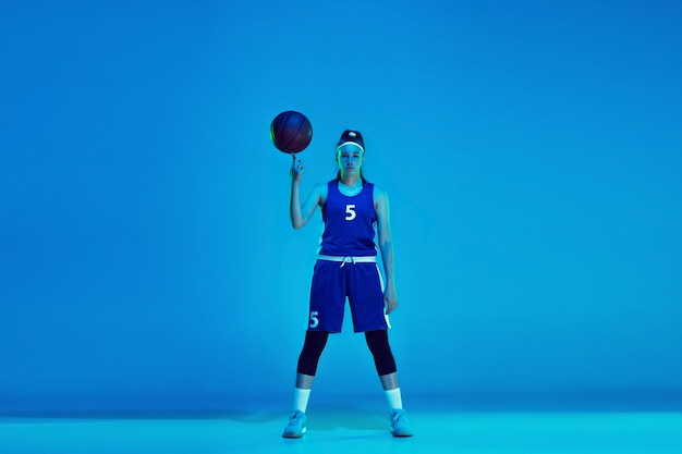 Jovem jogadora de basquete branca isolada em azul em luz de néon