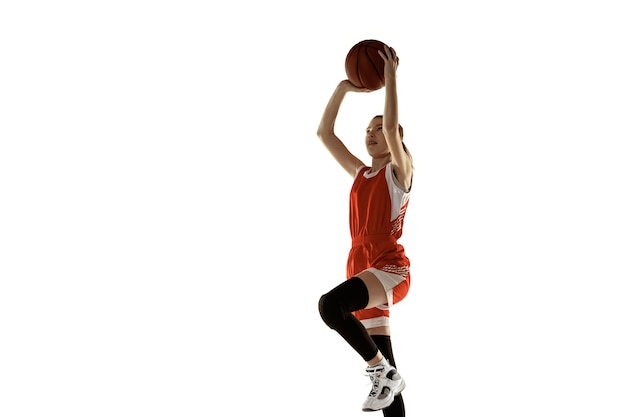 Foto grátis jovem jogadora de basquete feminino caucasiano em ação, movimento em salto isolado no fundo branco. garota esportiva redhair. conceito de esporte, movimento, energia e estilo de vida dinâmico e saudável. treinamento.