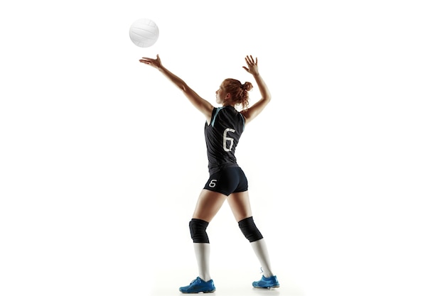 Jovem jogadora de voleibol isolada no fundo branco do estúdio. mulher em equipamentos de esporte e sapatos ou tênis, treinando e praticando. conceito de esporte, estilo de vida saudável, movimento e movimento.