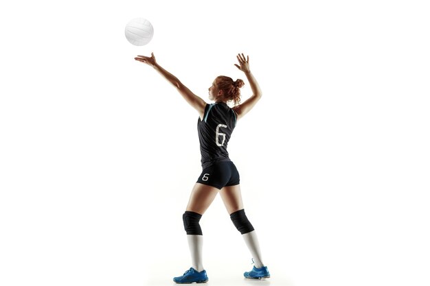 Jovem jogadora de voleibol isolada no fundo branco do estúdio. Mulher em equipamentos de esporte e sapatos ou tênis, treinando e praticando. Conceito de esporte, estilo de vida saudável, movimento e movimento.