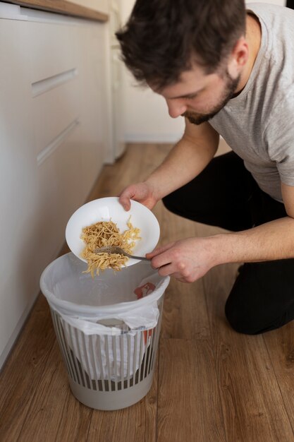 Jovem jogando comida no lixo