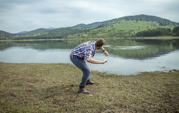 Jovem jogando pedra na água do lago