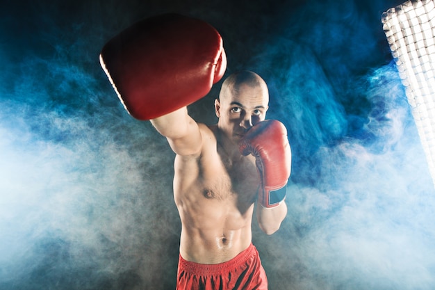 Foto grátis jovem kickboxing na fumaça azul