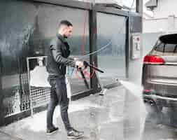 Foto grátis jovem lavando carro na estação de lavagem ao ar livre