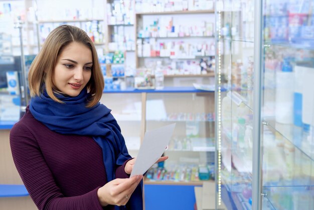 Jovem lendo prescrição em boticário