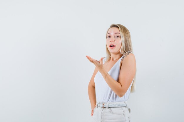 Jovem levantando a mão de maneira questionadora, usando uma blusa branca e parecendo um espaço confuso para texto