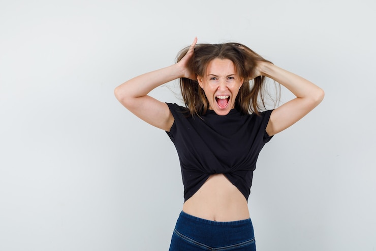 Foto grátis jovem levantando o cabelo enquanto gritava com uma blusa preta e parecendo louca