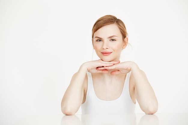 Jovem linda com pele limpa perfeita, sorrindo, sentado à mesa. Spa de beleza e cosmetologia.