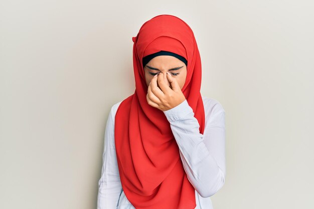 Jovem linda garota hispânica usando cachecol hijab islâmico tradicional cansado de esfregar o nariz e os olhos, sentindo fadiga e dor de cabeça. conceito de estresse e frustração.