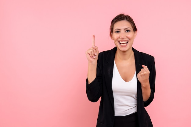 Jovem, linda mulher, de frente, com uma jaqueta escura no fundo rosa