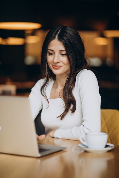 Foto grátis jovem linda mulher de negócios trabalhando no computador em um café