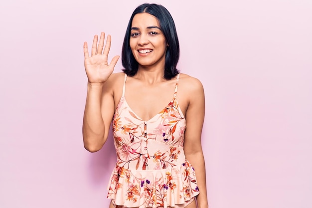 Foto grátis jovem linda mulher latina vestindo roupas casuais mostrando e apontando para cima com os dedos número cinco enquanto sorria confiante e feliz
