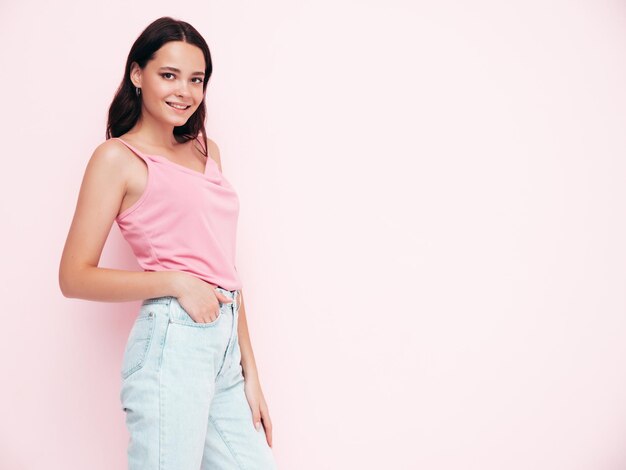 Jovem linda mulher sorridente em roupas da moda de verão Mulher despreocupada sexy posando perto da parede rosa no estúdio Modelo morena positiva se divertindo e enlouquecendo Alegre e feliz