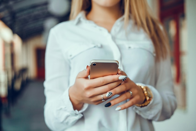 jovem linda usa um smartphone na rua, surfando na internet