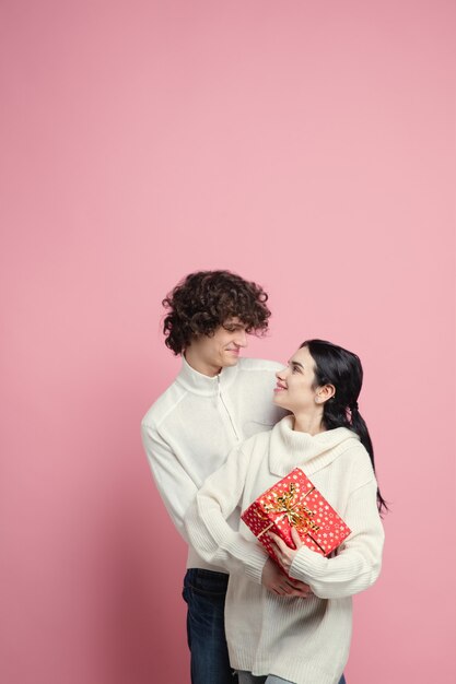 Jovem lindo casal apaixonado na parede rosa do estúdio