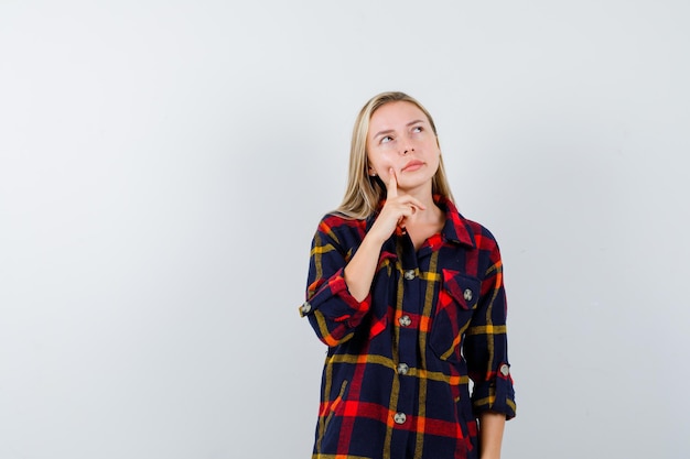 Jovem loira com uma camisa quadriculada pensando