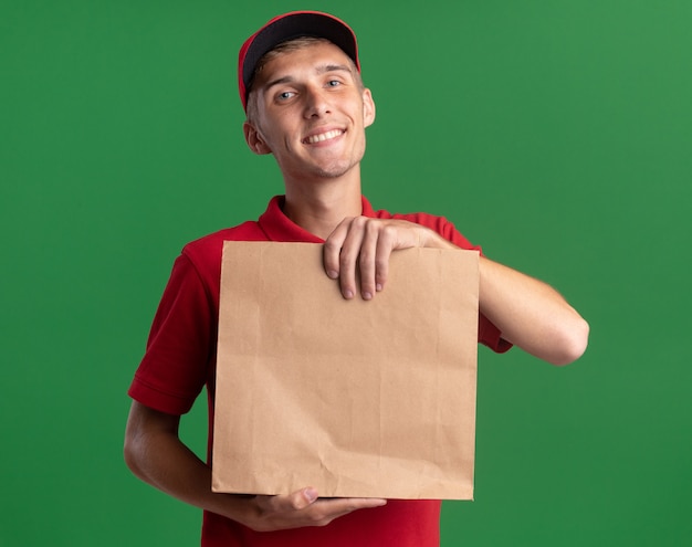 Jovem loira entregadora satisfeita segurando pacote de papel