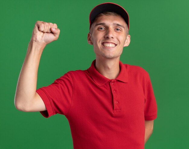 Foto grátis jovem loira entregadora sorridente com o punho erguido no verde