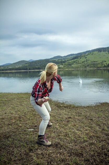 Jovem loira jogando pedras na água