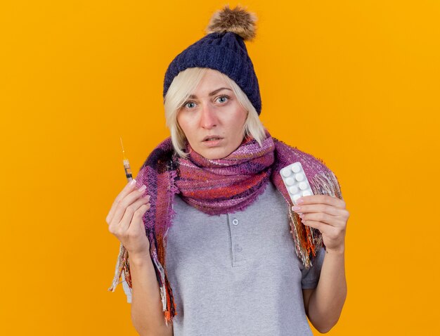 Jovem loira sem noção, mulher eslava usando chapéu de inverno e lenço segurando uma seringa