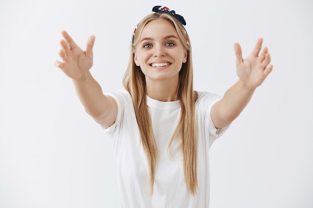 Foto grátis jovem loira simpática posando contra a parede branca