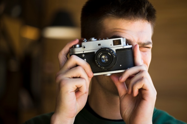 Jovem louco tirando fotos com a câmera vintage