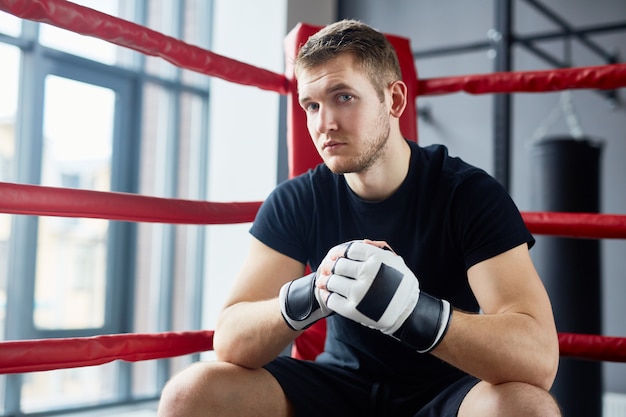 Jovem lutador sentado no ringue de boxe