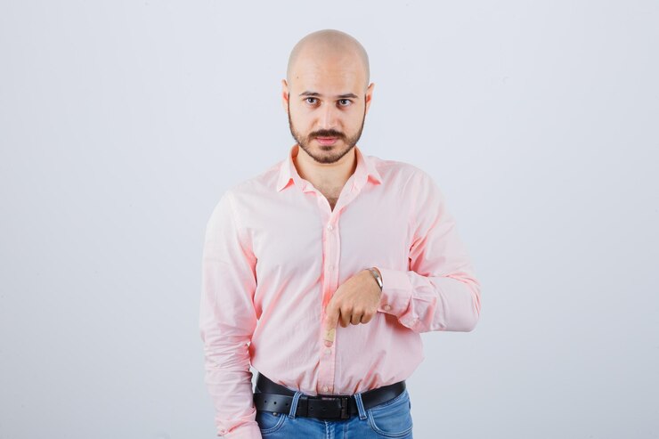 Foto grátis jovem macho apontando para baixo em camiseta, jeans e parecendo confiante, vista frontal.
