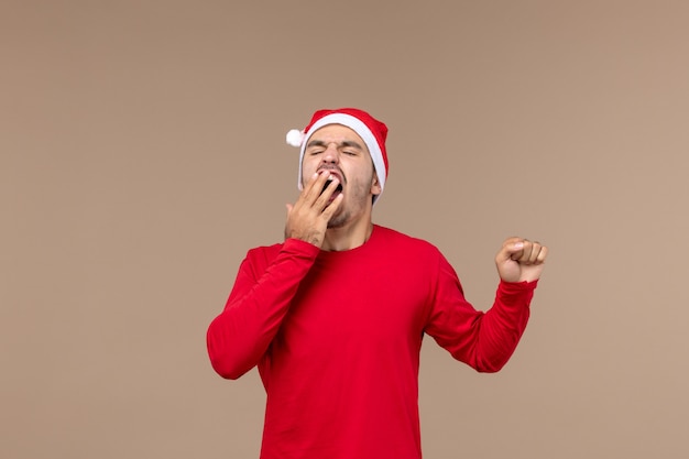 Jovem macho bocejando em um fundo marrom Natal emoção feriado macho