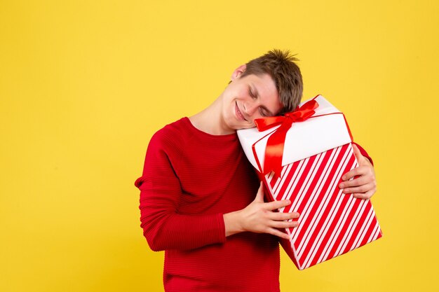 Jovem macho com grande Natal presente em um amarelo