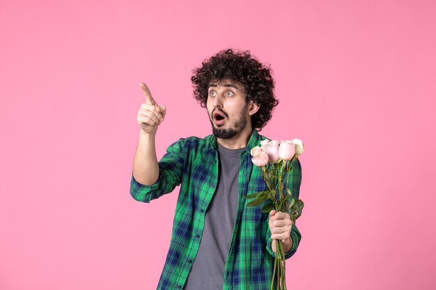 Jovem macho com rosas cor de rosa na frente