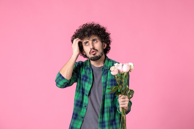 Jovem macho com rosas cor de rosa na frente